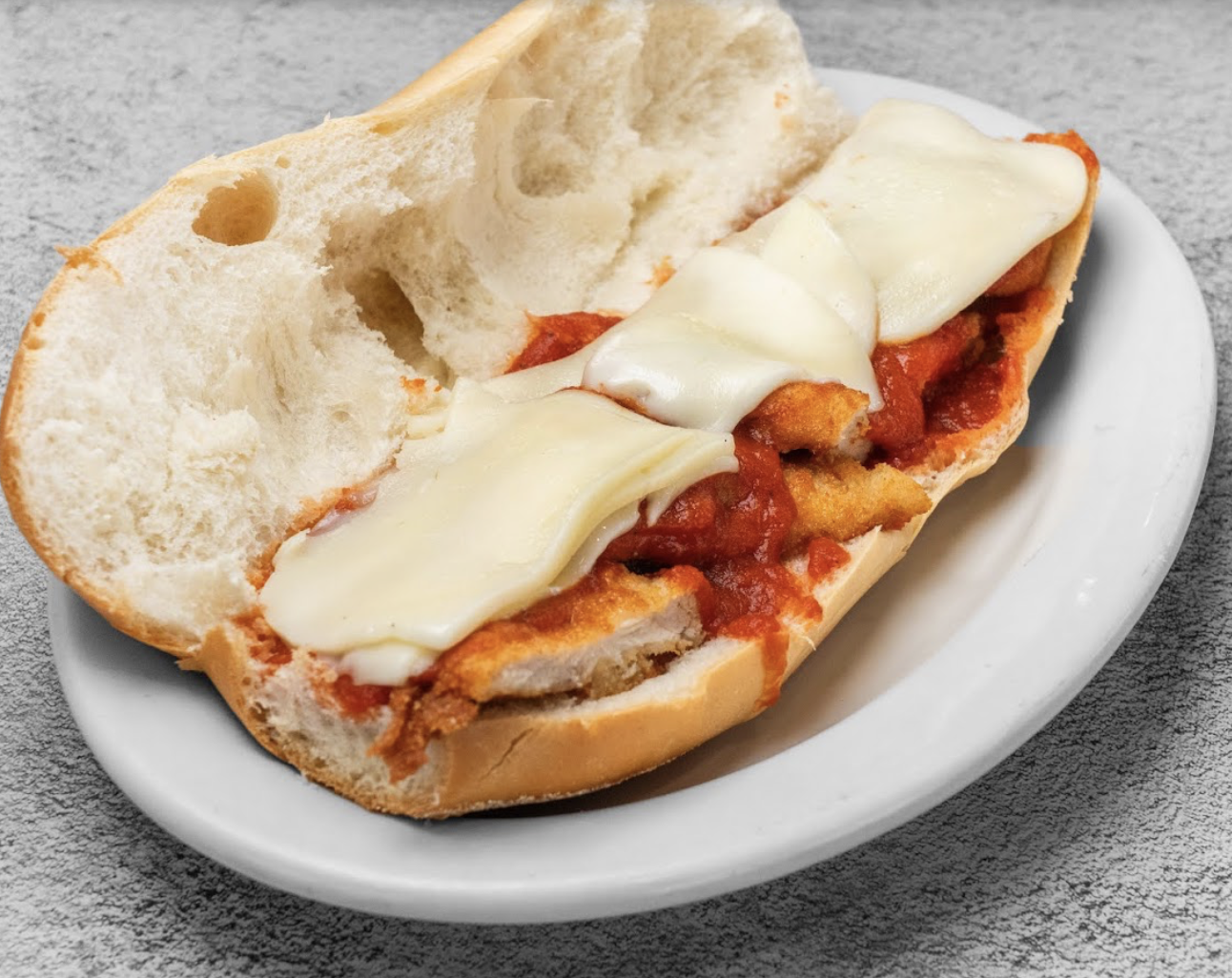 A chicken parmigiana hero with tomato sauce and melted mozzarella